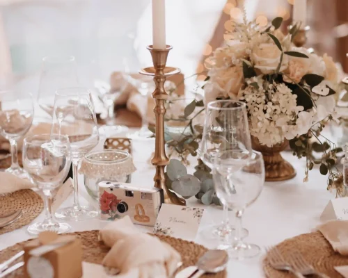 festlich gedeckter Tisch mit Hochzeitsdeko. goldene Kerzenständer, platzteller, goldenes Besteck und Blumen