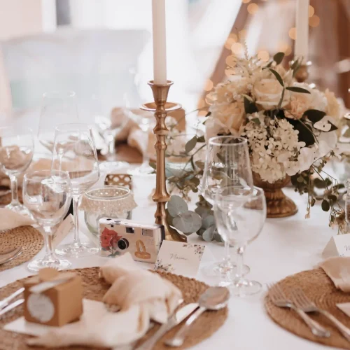 festlich gedeckter Tisch mit Hochzeitsdeko. goldene Kerzenständer, platzteller, goldenes Besteck und Blumen