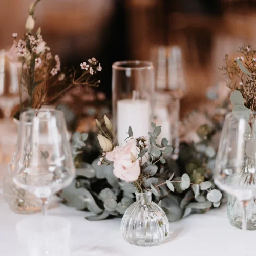 Hochzeitsdeko auf einem Tisch gedeckt mit transparenten vasen, Blumen und goldenen Besteck
